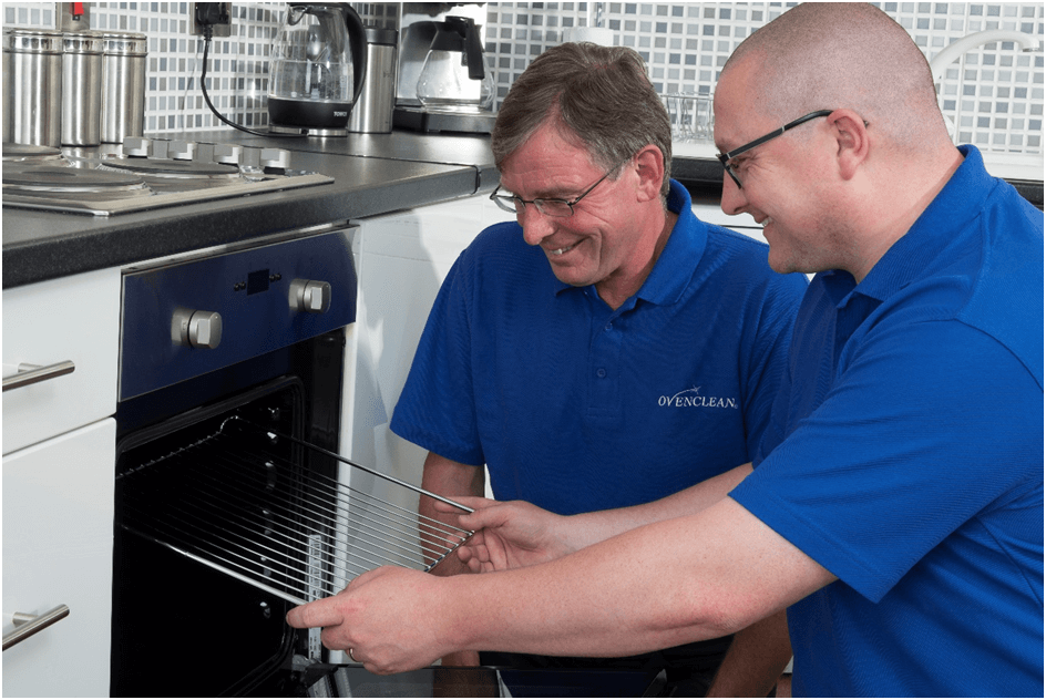 Two men cleaning an oven